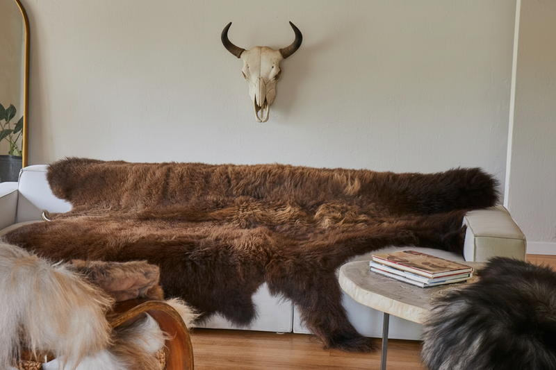 Brown fur-covered sofa in a room with a bull skull on the wall.