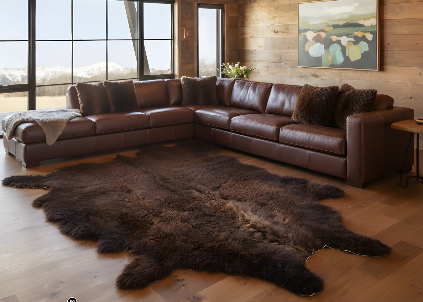 Brown leather sectional sofa in a room with wooden walls, large windows, and a bison rug.