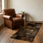 Brown leather armchair next to a fur rug on a wooden floor.