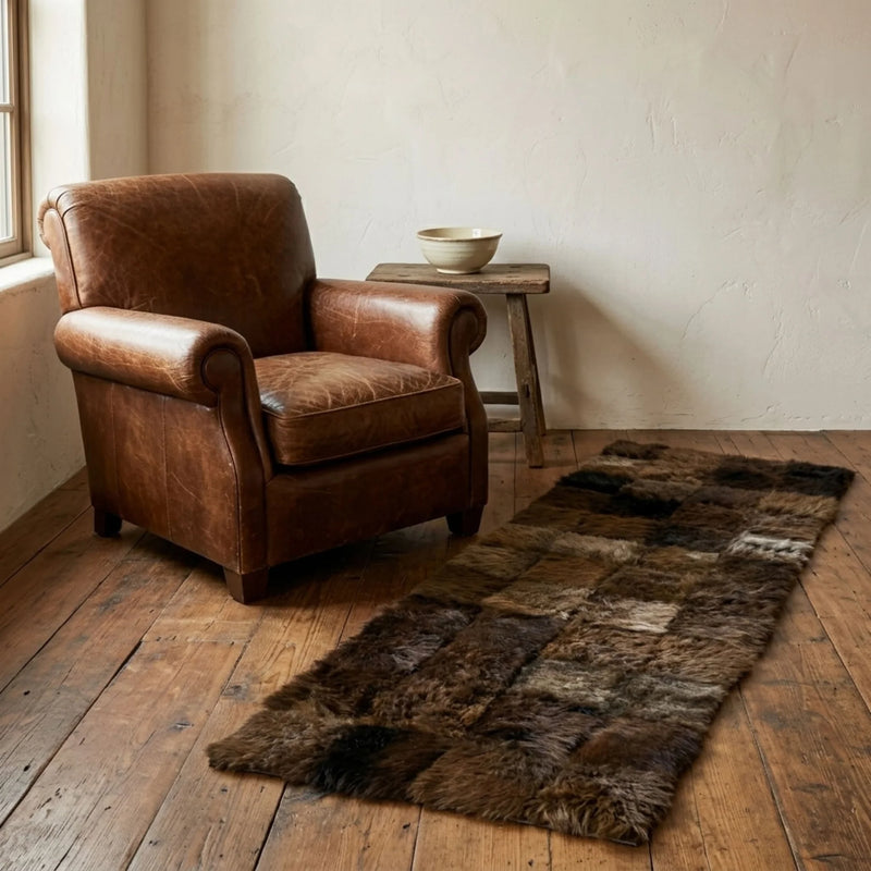 Brown leather armchair next to a fur rug on a wooden floor.