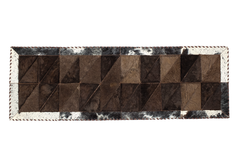 A rectangular patchwork area rug featuring a Bison center with cowhide edges in a tricolor pattern of brown, black, and white.