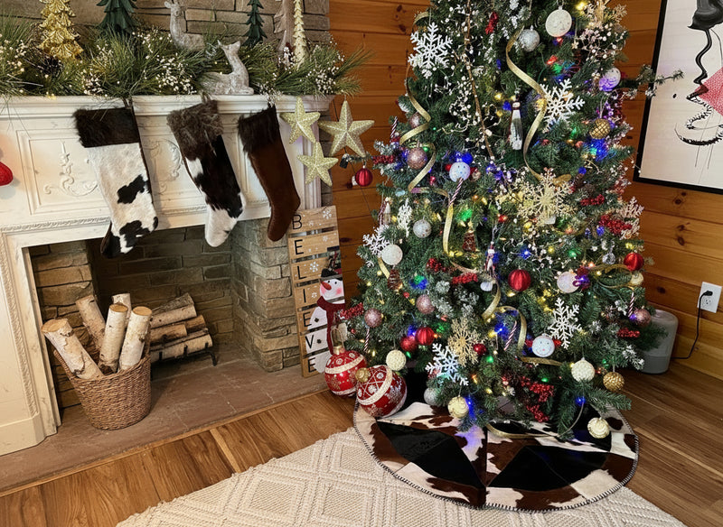 Decorated Christmas tree in a living room with stockings and a fireplace.
