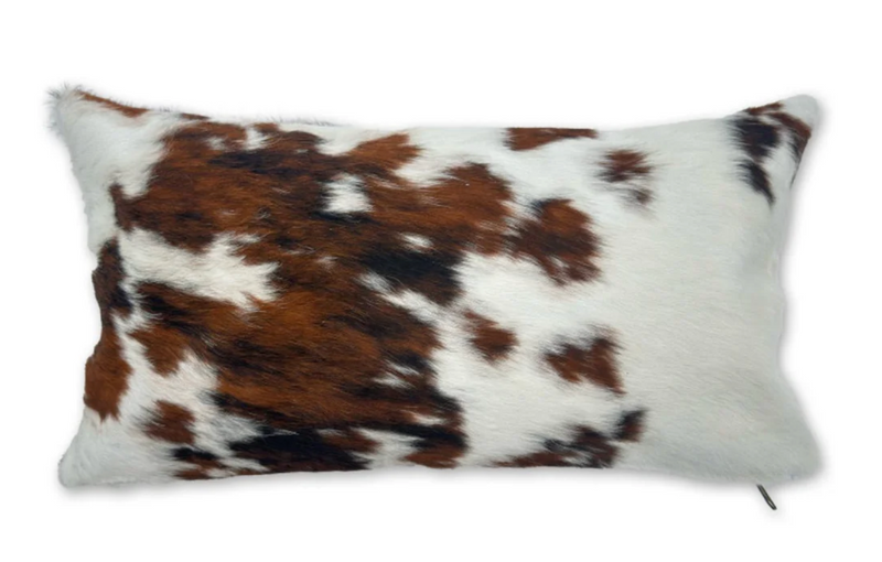 Rectangular pillow with brown, white, and black cowhide pattern on a white background