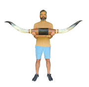 Man holding a large decorative item with long horns in a warehouse setting