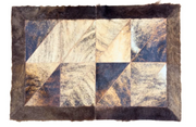 A square patchwork rug featuring a geometric quilted pattern of triangular sections in shades of brown, beige, and dark navy, finished with a thick dark brown fur border.