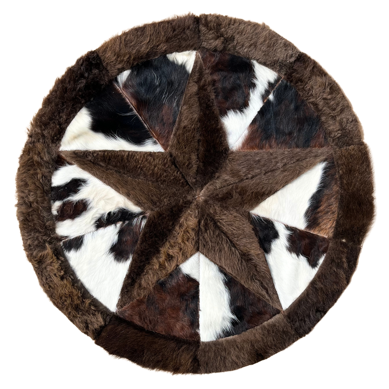 A round cowhide rug with a central star pattern and varying shades of brown, black, and white.